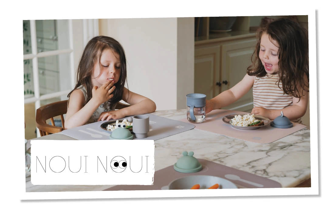 Zwei Kinder sitzen am Essenstisch, auf welchem Tisch-Sets von noui noui liegen