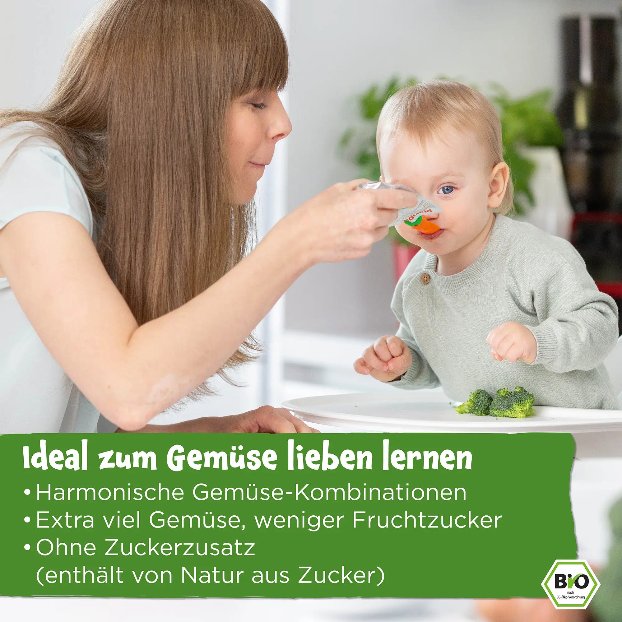 Mutter füttert ihr Baby mit einem Bio Gemüse-Quetschie von Pumpkin Organics; Ideal zum Gemüse lieben lernen, harmonische Gemüse-Kombinationen, extra viel Gemüse, weniger Fruchtzucker, ohne Zuckerzusatz (enthält von Natur aus Zucker)