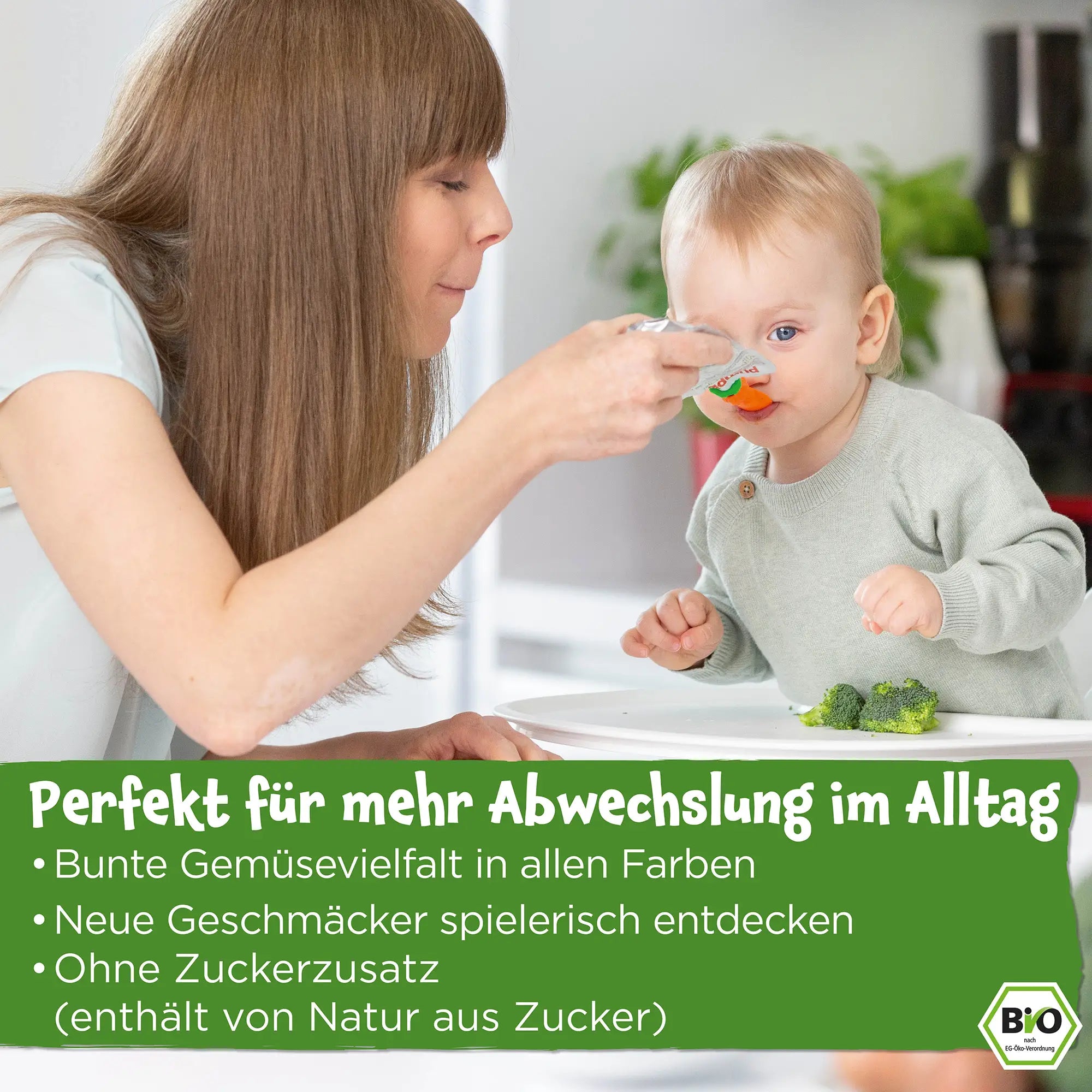 Eine Mutter füttert ihr Baby mit einem Bio Gemüse-Quetschie; Perfekt für kleine Gemüsemuffel; besonders mild im Geschmack; mit Getreide und angenehm dickflüssiger Textur; Ohne Zuckerzusatz (enthält von Natur aus Zucker)