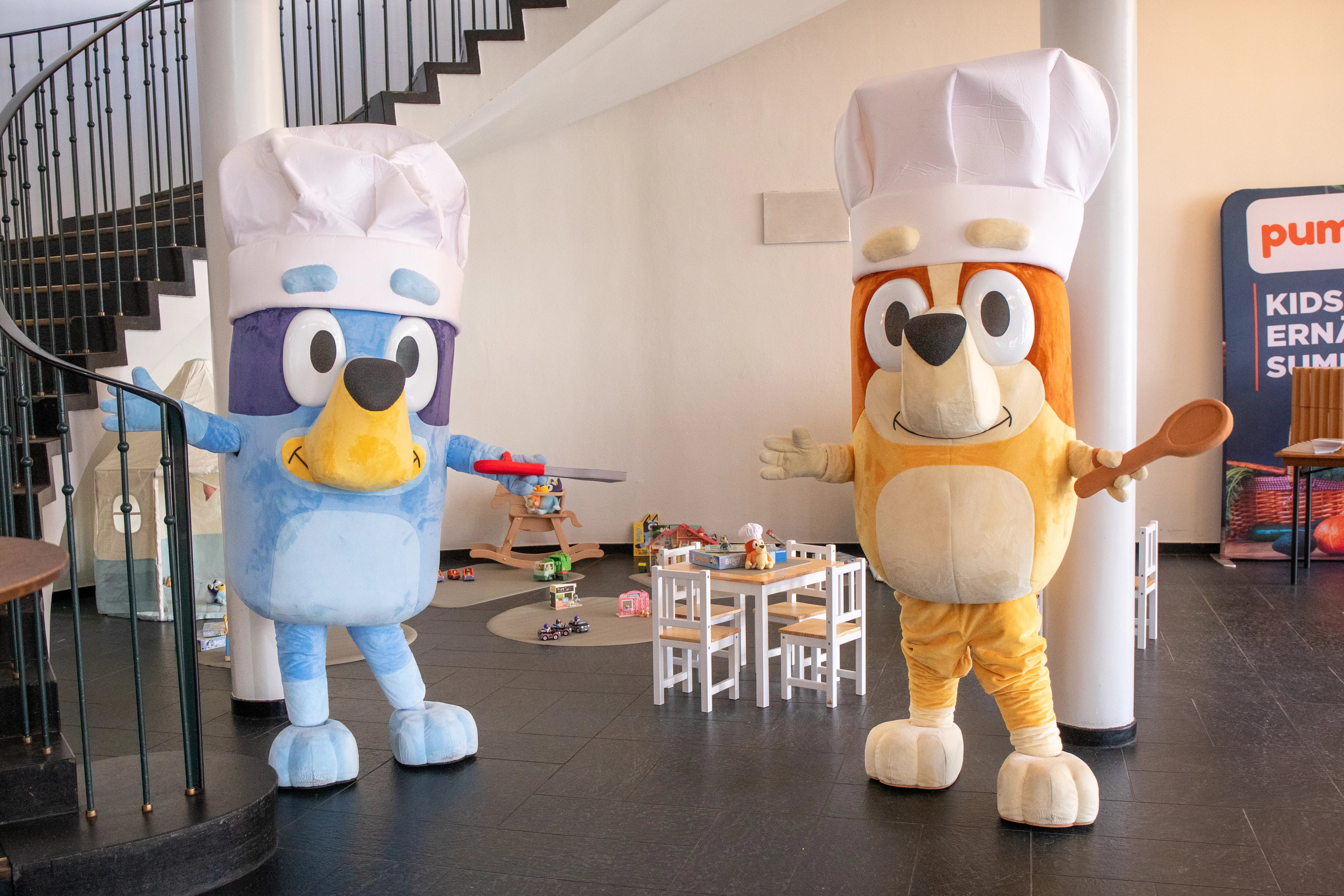 Die Maskottchen Bluey und Bingo im Foyer der alten Kongesshalle, im Hintergrund eine Spielecke