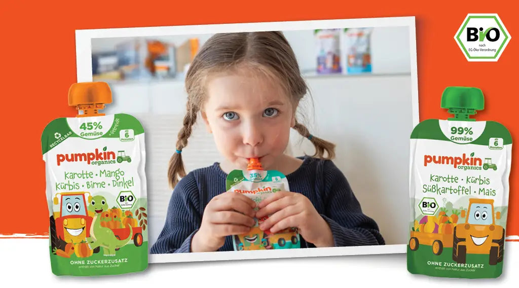 Mädchen isst einen Bio Gemüse-Quetschie; zwei Bio Gemüse-Quetschies von Pumpkin Organic im Vordergrund 