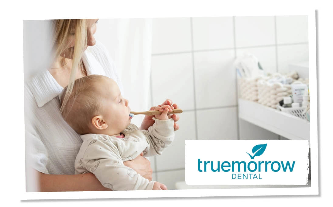 Mutter mit Baby im Arm, das Baby hat eine Zahnbürste von truemorrow im Mund
