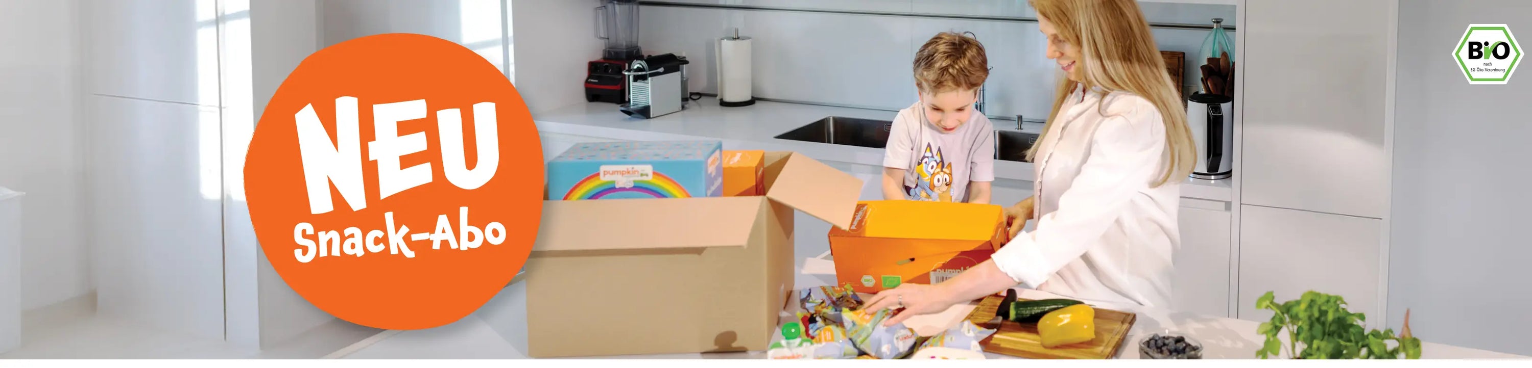 Neu: Snack-Abo ; Mutter und Kind packen ihre Abo-Bestellung von Pumpkin Organcis in der Küche aus